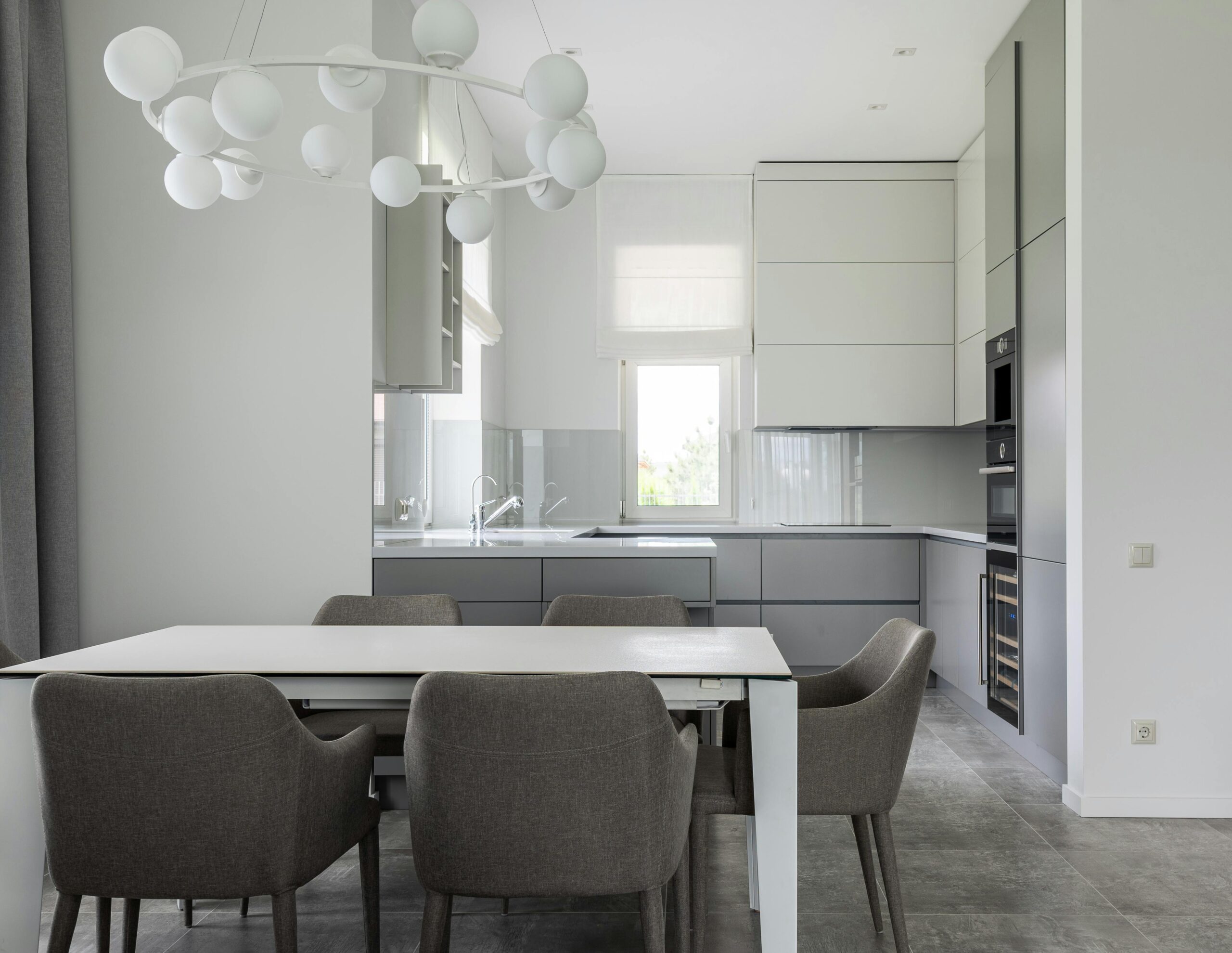Sleek modern dining room with gray chairs, white table, and contemporary lighting.
